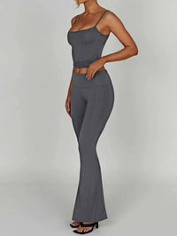 Woman wearing a gray sleeveless top and flared pants on a plain background