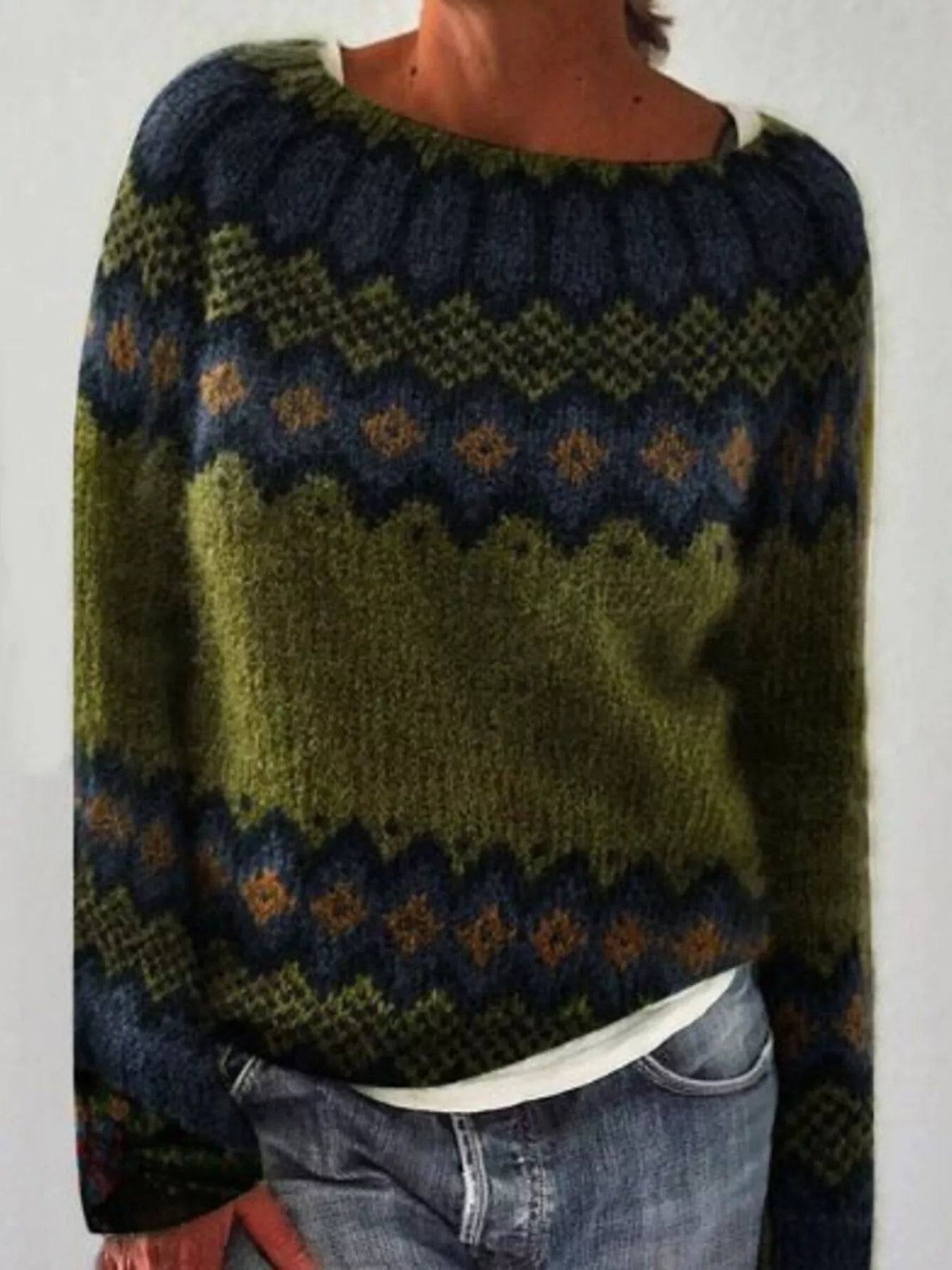 Person wearing a patterned sweater with green, blue, and brown colors on a plain background