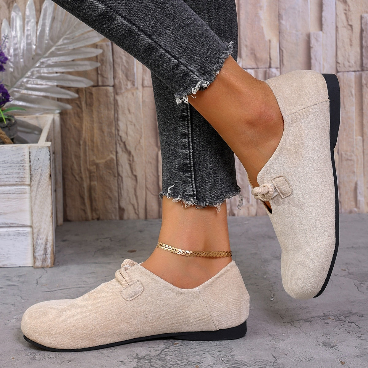 Beige loafers worn with black jeans on a neutral background