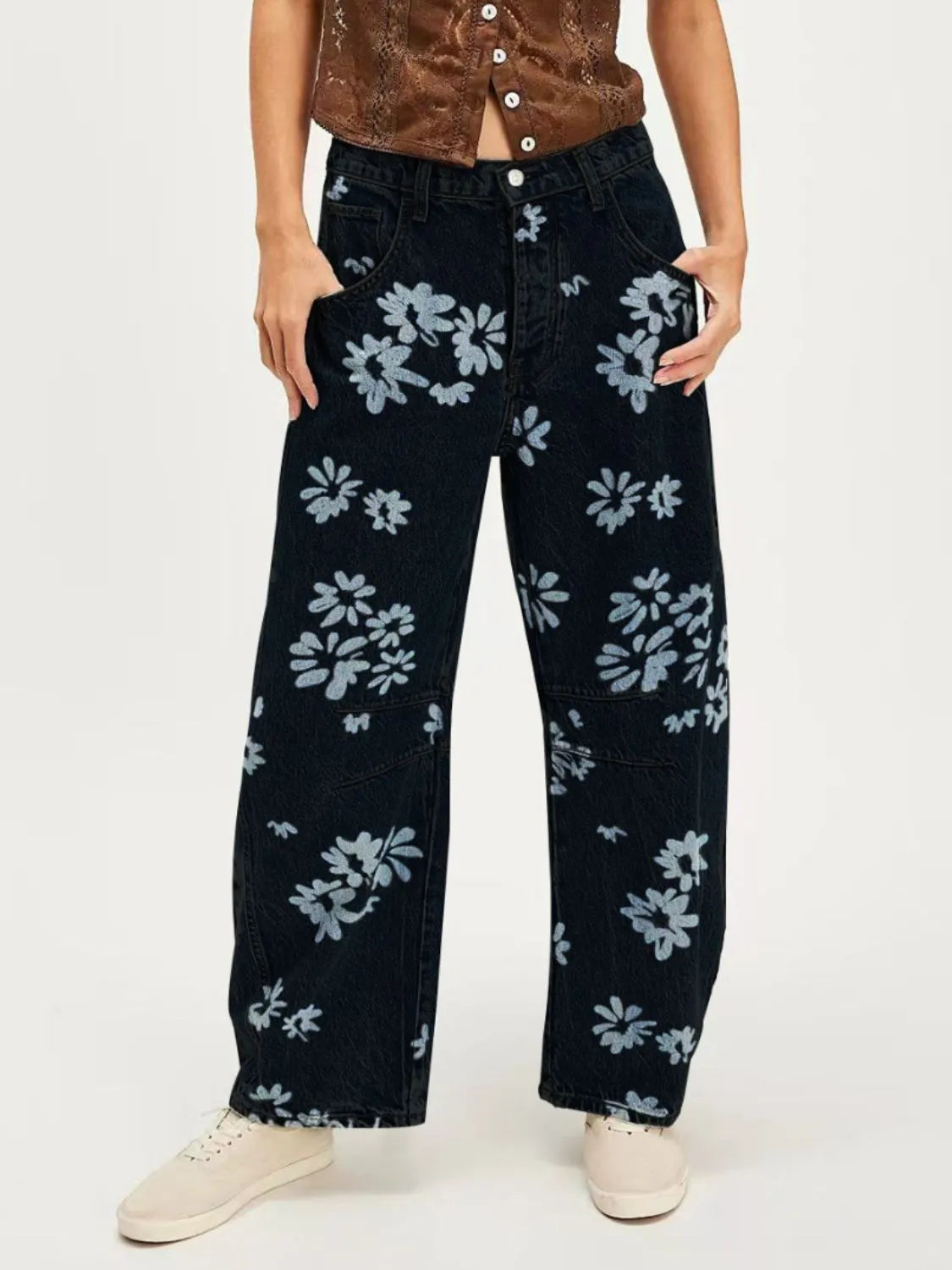 Person wearing black floral-patterned jeans on a white background