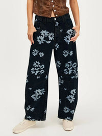 Person wearing black floral-patterned jeans on a white background