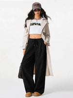 Person wearing a white jacket, white crop top, black pants, and brown shoes on a white background