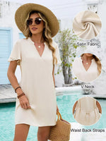 Woman wearing a cream-colored dress with details highlighted, standing by a pool.