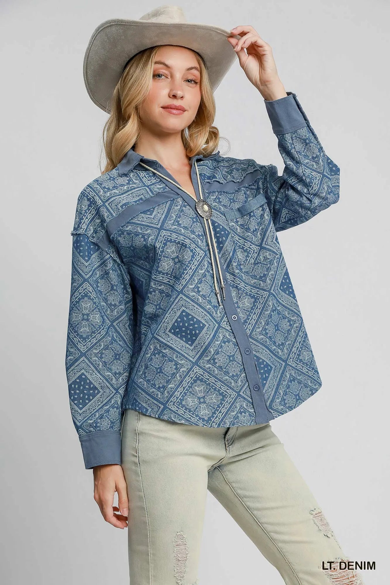 Woman wearing a blue patterned jacket and beige hat on a white background
