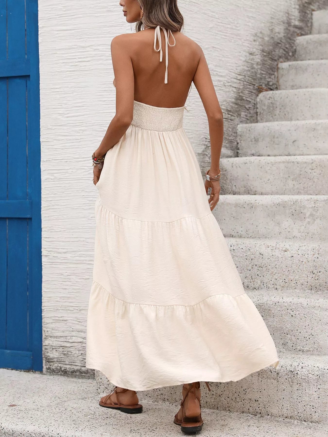 Woman in a white dress standing on a staircase with a blue door in the background
