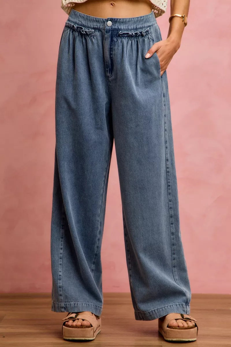 Wide-leg jeans worn by a person on a pink background