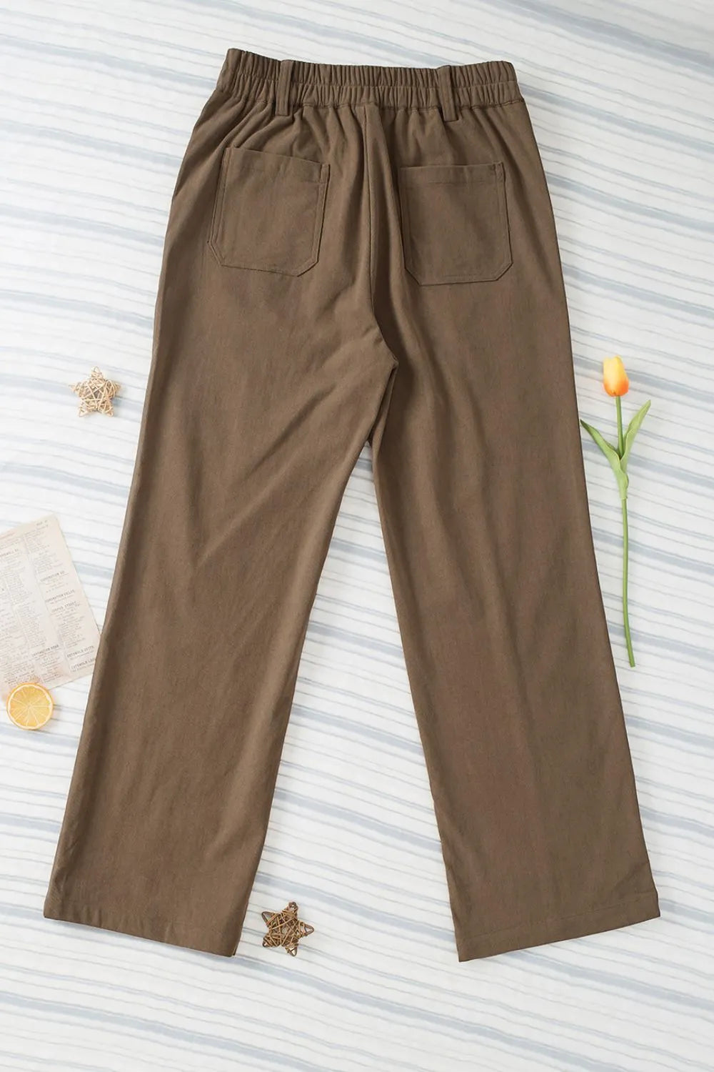 Brown pants on a textured white background with decorative elements.