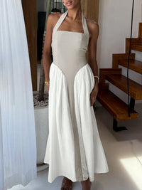 Woman wearing a beige halter neck dress with a white skirt in an indoor setting.