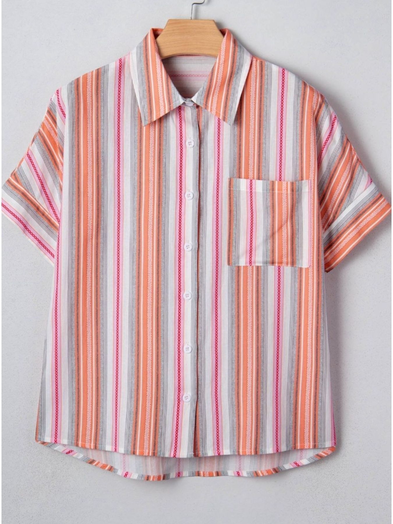 Striped shirt with short sleeves on a hanger against a light gray background