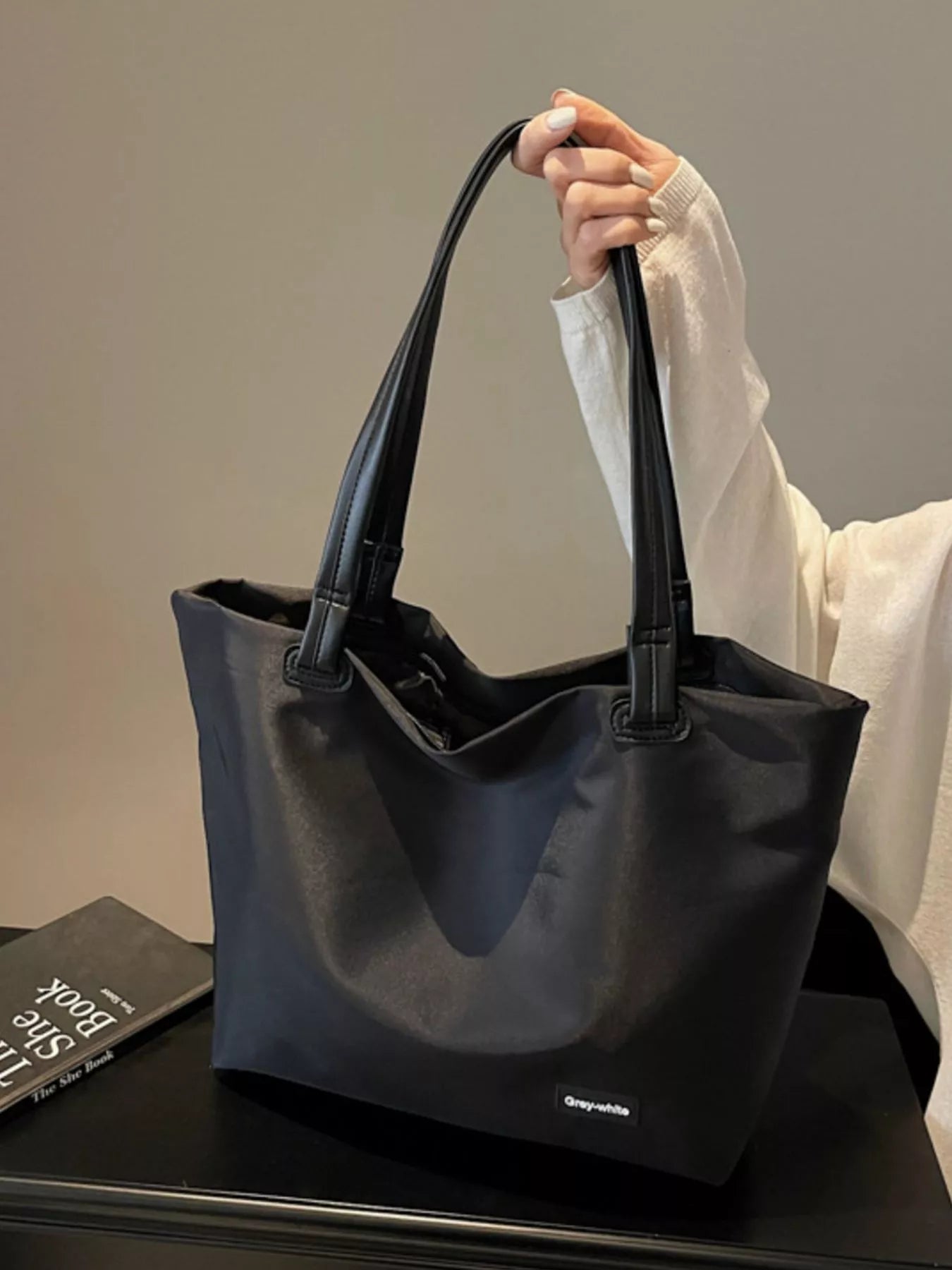 Person holding a black tote bag with a blurred background