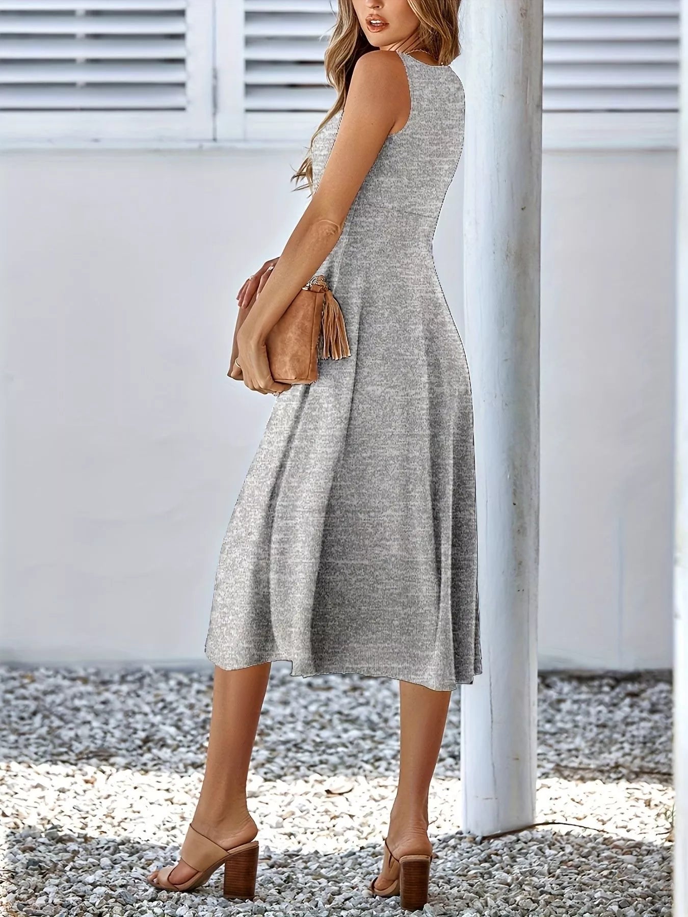 Woman wearing a gray sleeveless dress with a white background