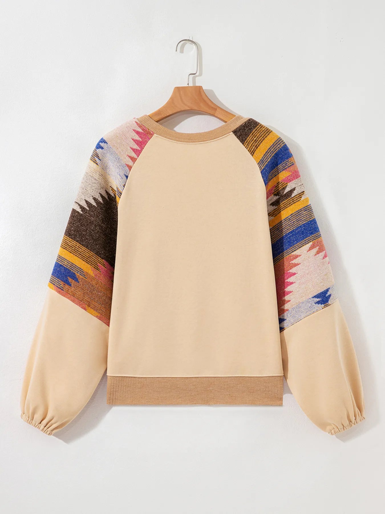 Beige sweatshirt with colorful patterned sleeves on a hanger against a white background