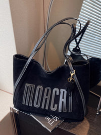 Black handbag with 'MOCA' branding on a wooden surface