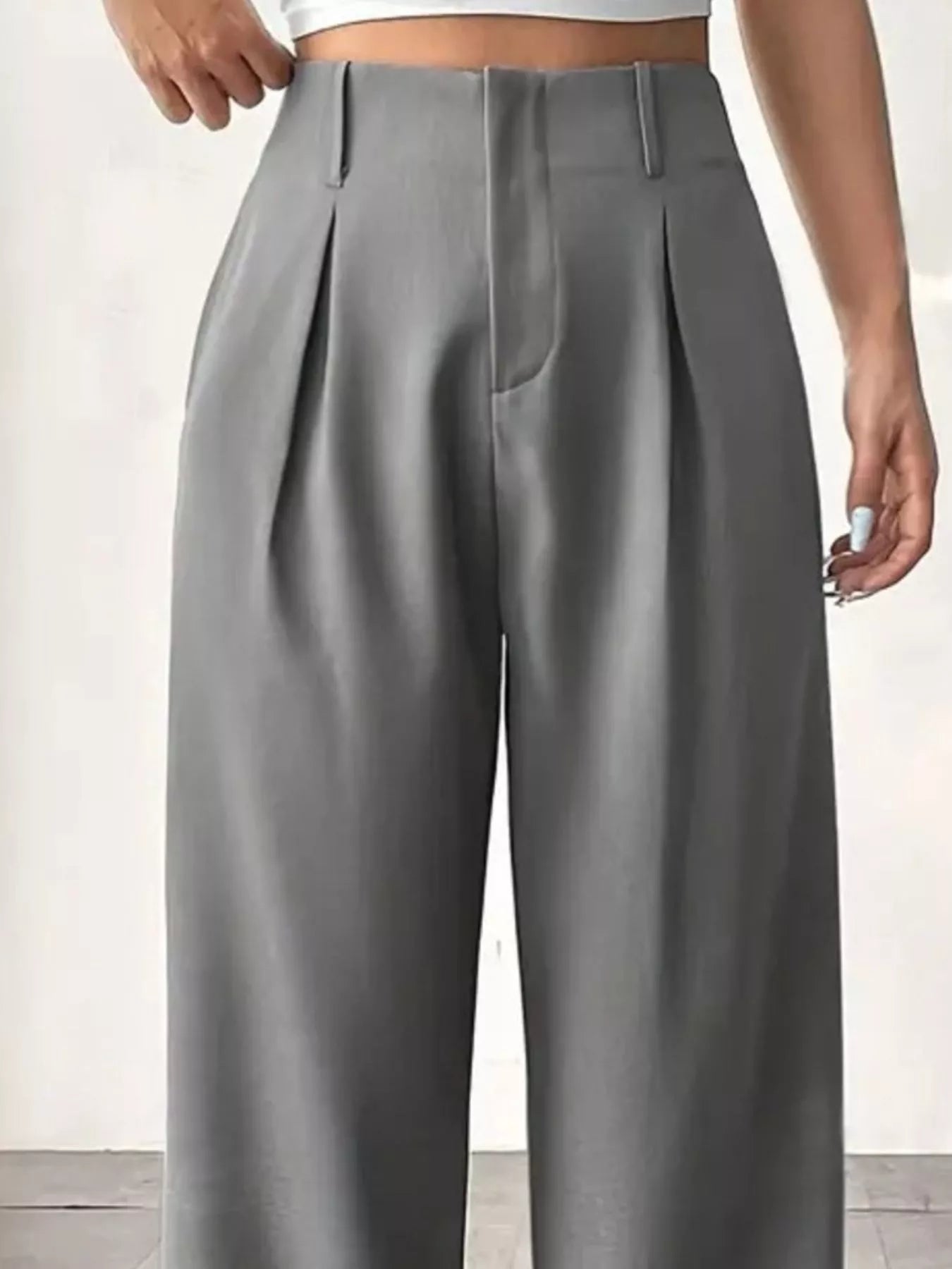 Gray pleated pants worn by a person on a light background