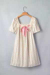 Floral dress with a pink bow on a hanger against a gray background