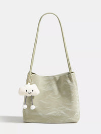 Light green handbag with a cloud-shaped charm on a white background