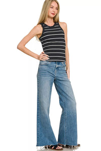 Woman wearing a black and white striped tank top and blue jeans on a white background