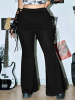 Person wearing black flared pants with a guitar and other musical instruments in the background