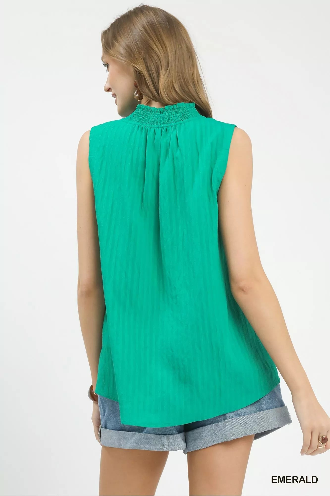 Woman wearing a green sleeveless top with a plain background