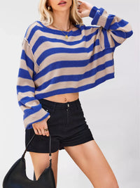 Person wearing a blue and beige striped sweater with black shorts on a white background