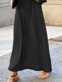 Person wearing a long black dress on a stone pavement.