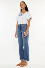 Woman wearing a white blouse with blue patterns and blue jeans on a white background