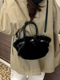 Person wearing a beige coat holding a black fur handbag.