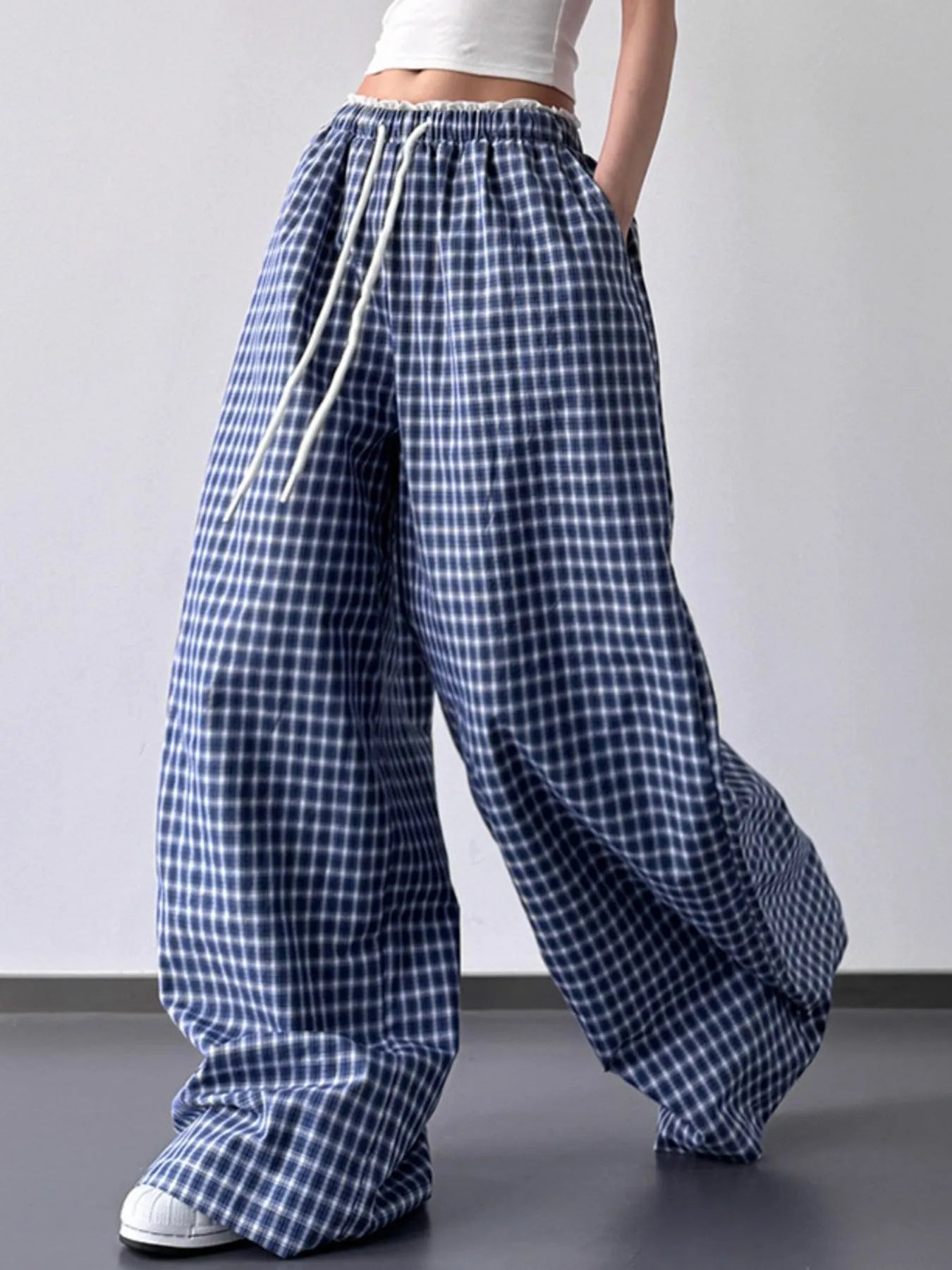 Blue and white checkered pants worn by a person on a plain background