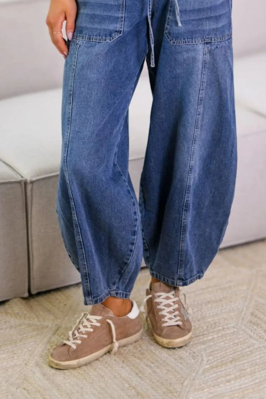 Person wearing blue jeans and brown sneakers on a carpeted floor.