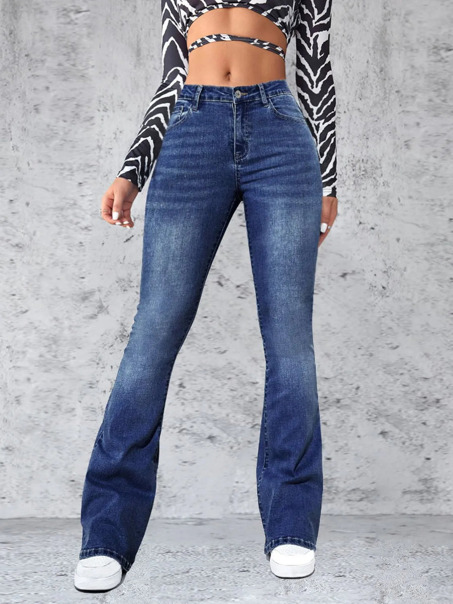 Person wearing blue jeans and a zebra-patterned top against a gray concrete wall.