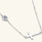 Silver necklace with a cross pendant and round gemstone on a white background