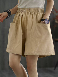 Beige shorts worn by a person on a dark background