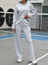 Person wearing a gray tracksuit on a tennis court