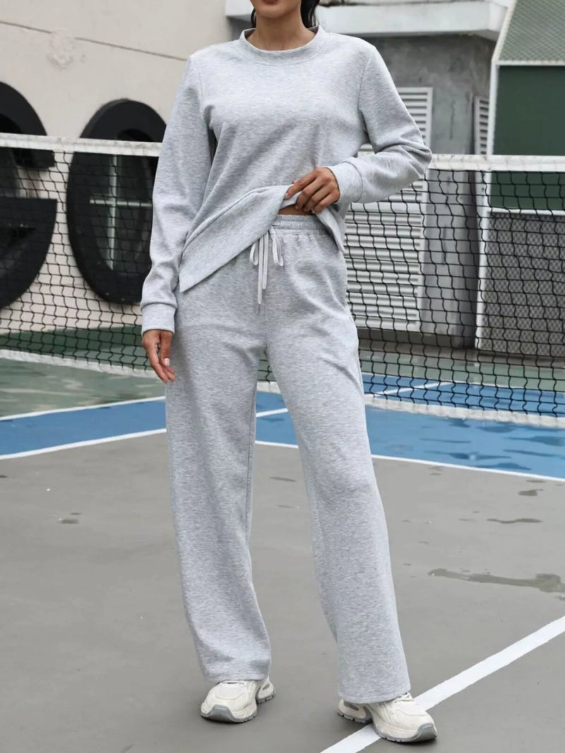 Person wearing a gray tracksuit on a tennis court