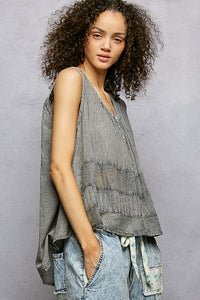 Woman wearing a sleeveless, layered top with a gray background