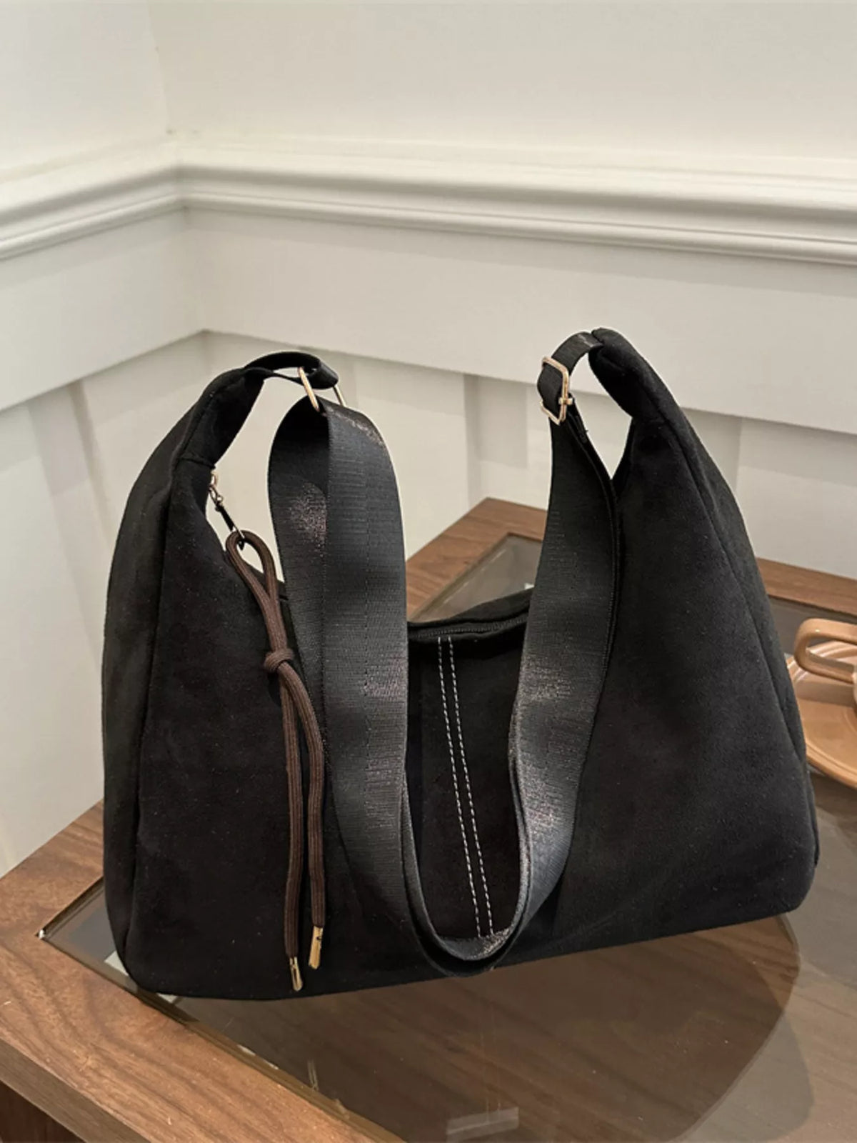 Black handbag on a wooden surface with a neutral background