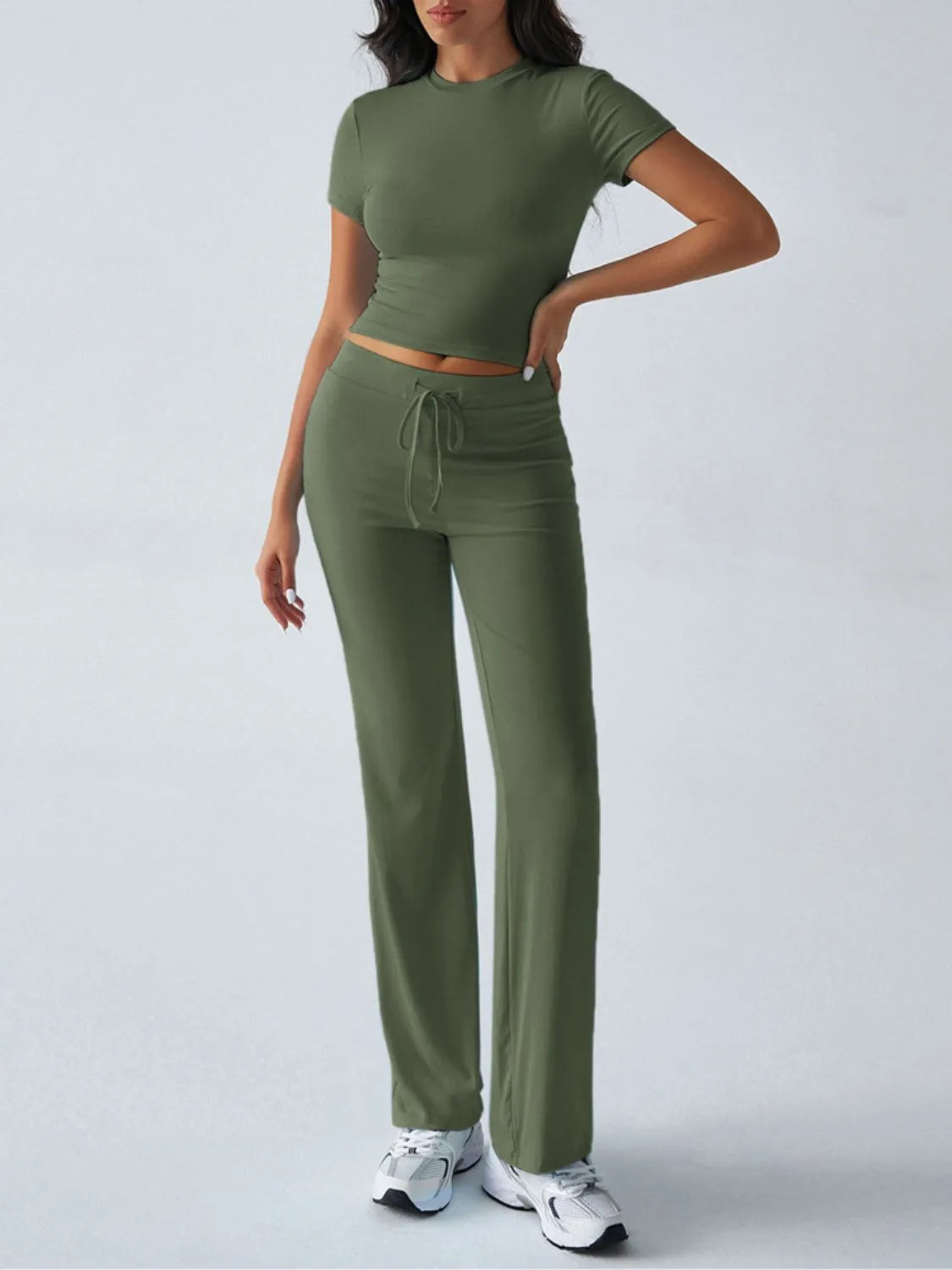 Woman wearing a green outfit with a top and pants on a white background