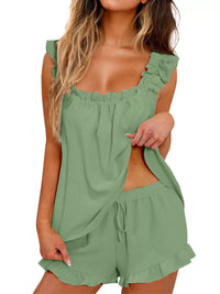 Woman wearing a green romper with ruffled details on a white background