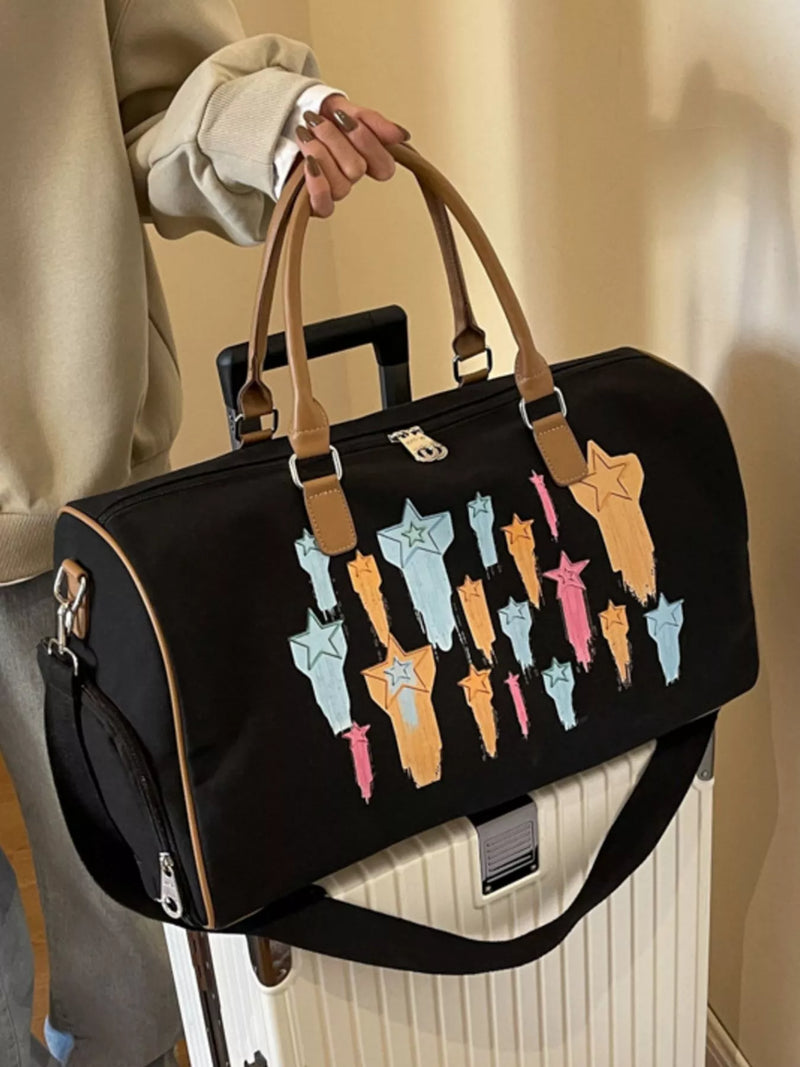 Black duffel bag with colorful designs held by a person against a neutral background