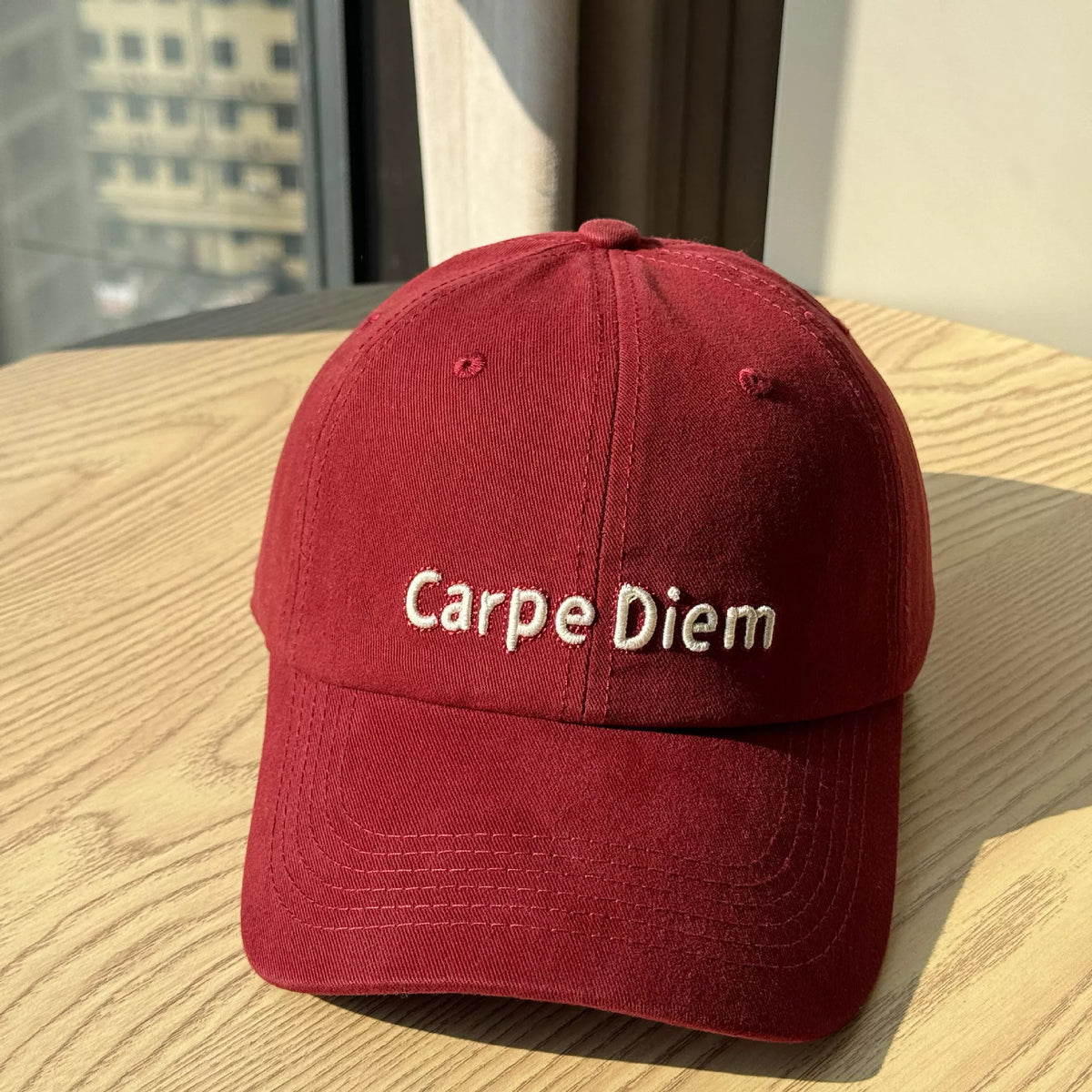 Red cap with 'Carpe Diem' text on a wooden surface