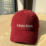 Red cap with 'Carpe Diem' text on a wooden surface