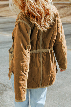 Person wearing a brown quilted jacket with a blurred background