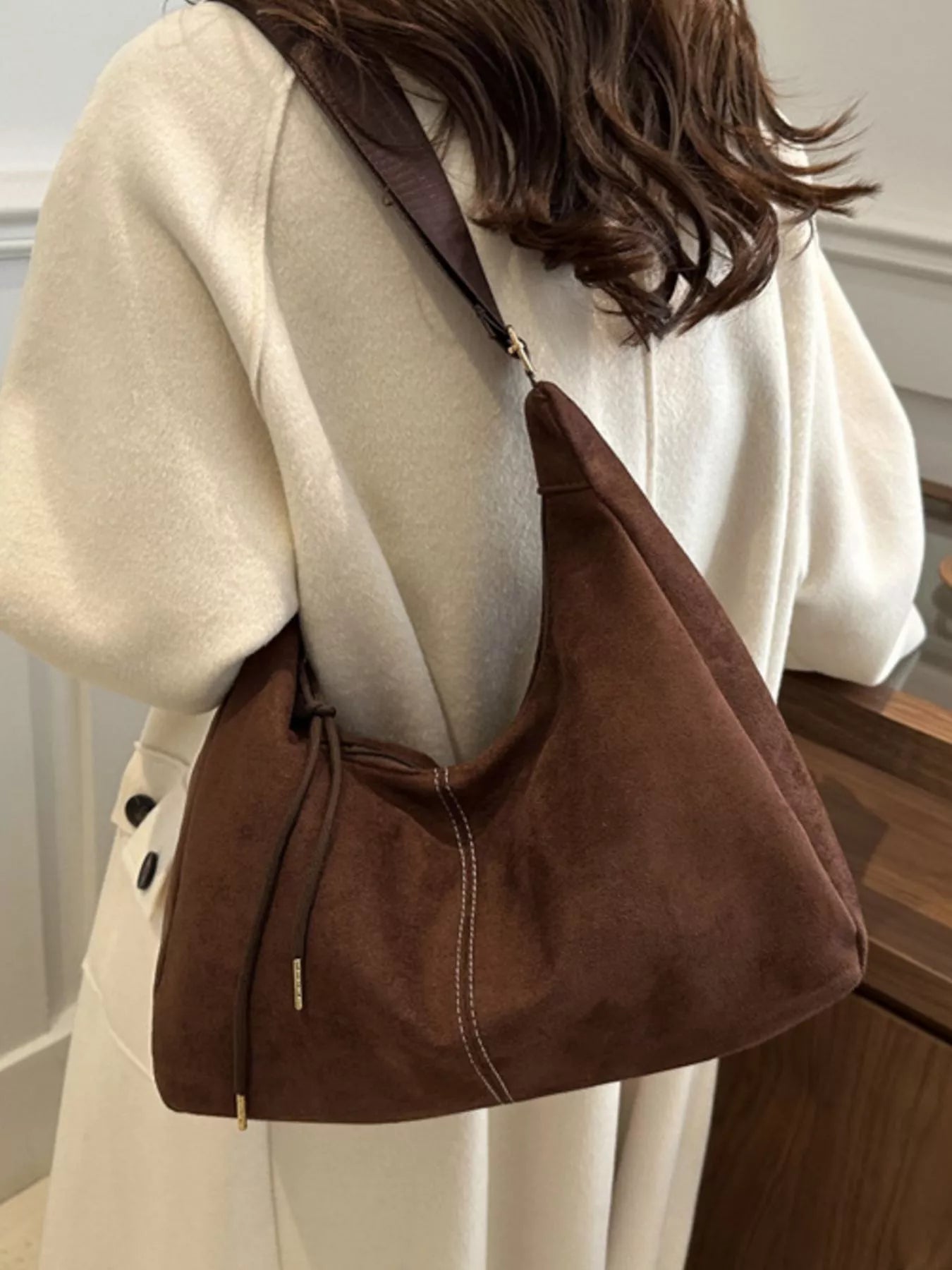 Brown shoulder bag worn by a person in a neutral setting