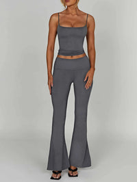 Woman wearing a gray sleeveless top and flared pants on a plain background
