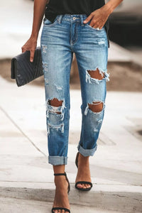 Person wearing ripped blue jeans with a blurred background