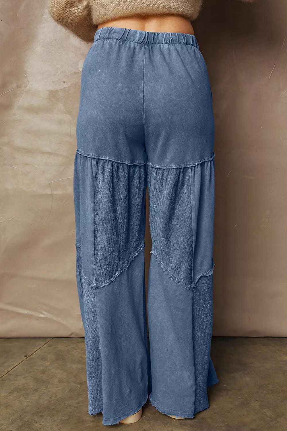 Blue layered pants worn by a person against a beige background