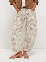 Person wearing floral pants and a brown jacket on a white background
