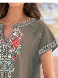 Woman wearing a green embroidered dress with floral patterns.
