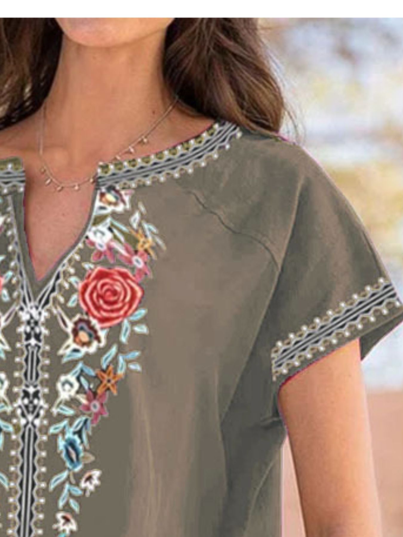 Woman wearing a green embroidered dress with floral patterns.