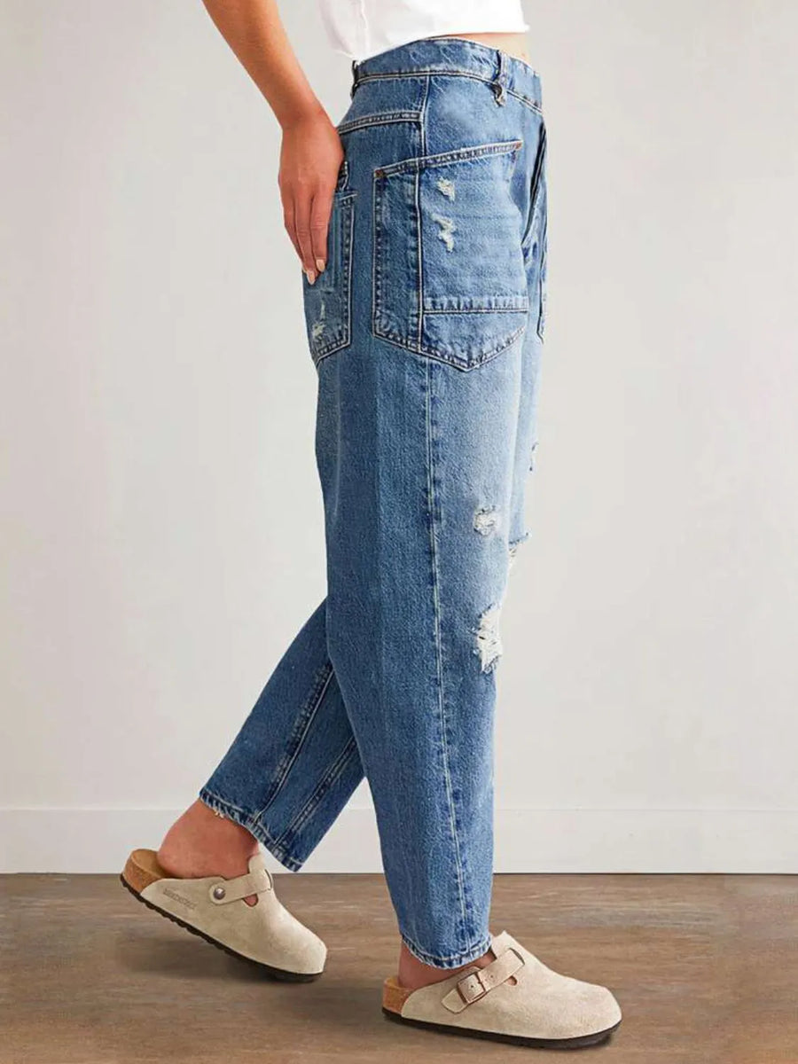 Person wearing blue jeans and beige shoes on a plain background